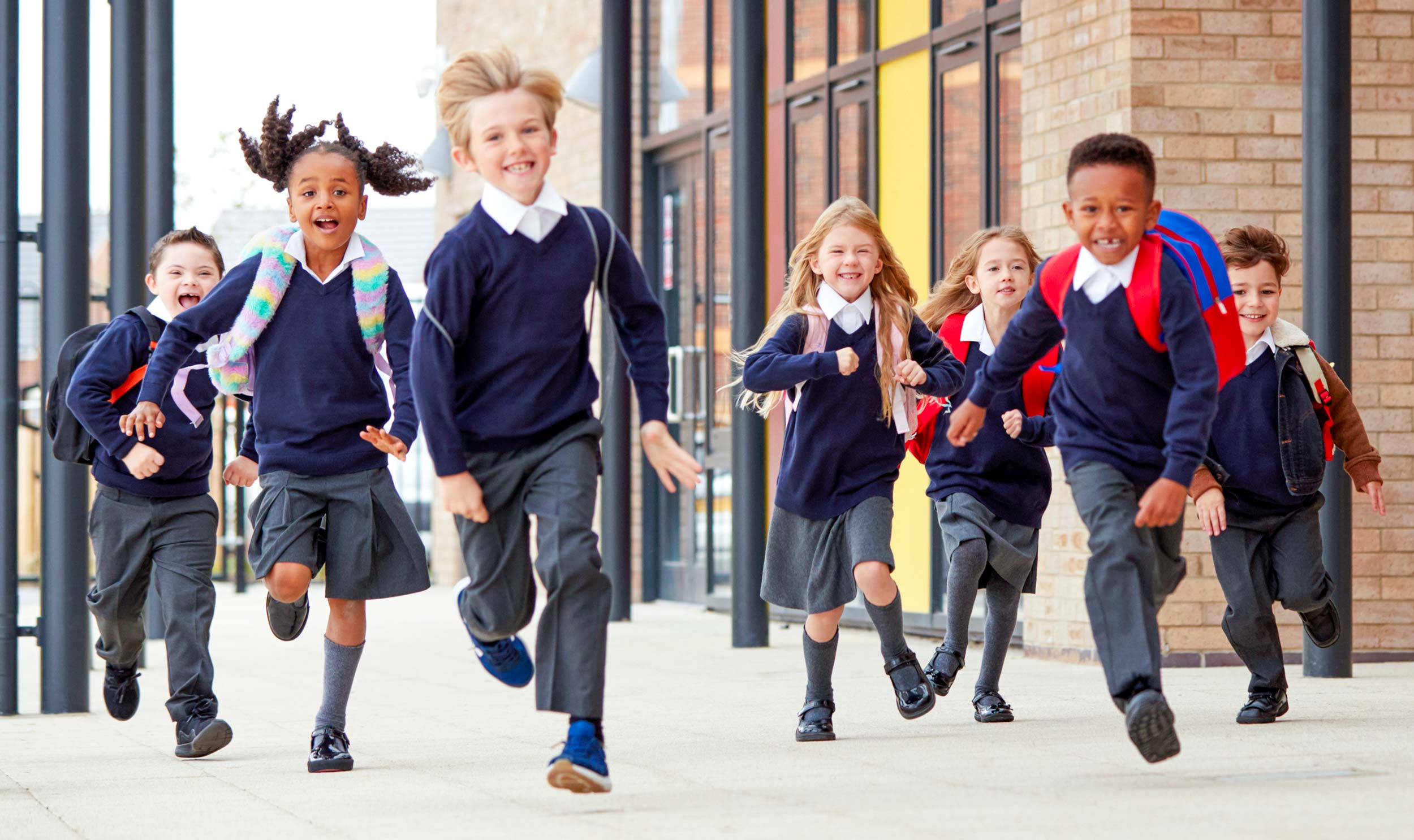 Children in school uniform running outside school towards camera